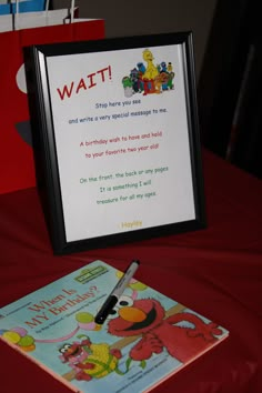 a sesame street birthday card with a pen and scissors on a red table cloth next to a sign that says wait