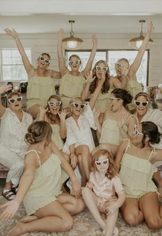 a group of women in dresses and sunglasses posing for a photo with their arms up