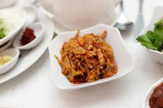 a white bowl filled with food sitting on top of a table next to other bowls