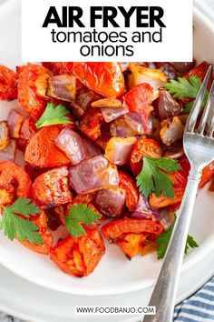 an air fryer with tomatoes and onions in it on a plate next to a fork