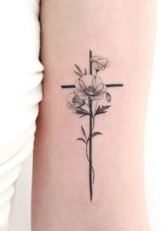 a cross and flowers tattoo on the arm