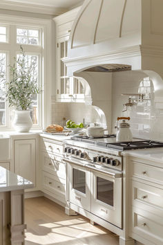 a white kitchen with an oven, stove and counter tops in front of two windows