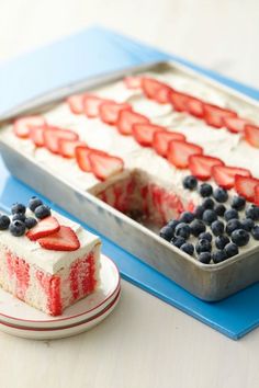 a red, white and blue cake with strawberries on top is sitting next to a tin pan