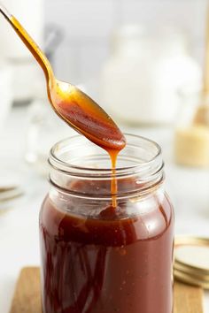 a spoon full of sauce on top of a wooden cutting board