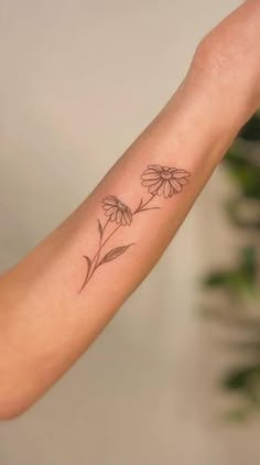 a woman's arm with a small flower tattoo on the left side of her arm