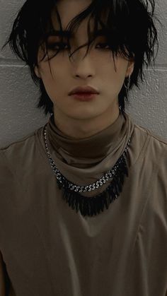 a woman with black hair wearing a brown shirt and choker necklace on her neck