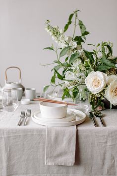 a table set with flowers and silverware