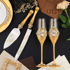 two champagne flutes are sitting next to each other on a table with gold and white decorations