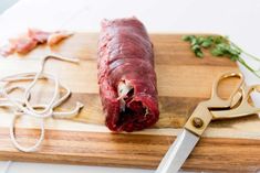 a piece of raw meat on a cutting board with a knife