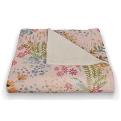 a pink blanket with flowers and leaves on it, next to a white pillow cover