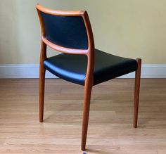 a wooden chair sitting on top of a hard wood floor next to a white wall