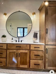 a bathroom with wooden cabinets and a round mirror