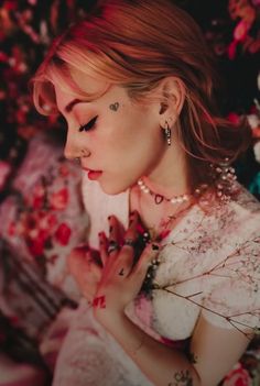 a woman in a white dress with flowers around her neck and hands on her chest