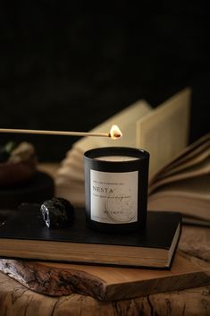 a candle sitting on top of a wooden table next to an open book and a lit match