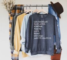 Our City Sweatshirt is one to love! These jet-set cities will have you dreaming of your next adventure! Our super soft sweatshirt is equally great around town, on the plane, or just lounging around! Looking for additional graphic chic apparel? Check these out: https://www.etsy.com/shop/TheGraphicPeach?ref=seller-platform-mcnav§ion_id=30396058 Our shop uses direct-to-garment printing to make our products. The design ink is sprayed on, then allowed to soak into the fibers of the garment. This proc Cold Sweatshirt, City Sweatshirt, Alexander Hamilton, Custom Sweatshirts, Funny Sweatshirts, Fall Sweatshirt, Shirt Mockup, Look Plus, Teacher Shirts