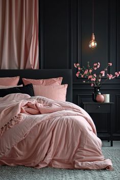 a bedroom with black walls, pink bedding and flowers in vases on the floor