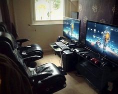 two computer monitors sitting next to each other in front of a window on top of a carpeted floor