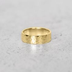 a close up view of a gold wedding ring on a marble surface, with the top section