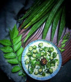 a blue plate topped with broccoli soup next to green beans and leafy greens