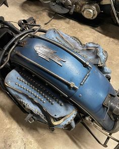 an old blue motorcycle sitting on top of a floor