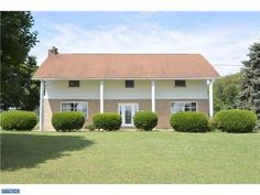 a large white house sitting on top of a lush green field