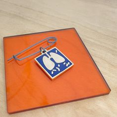 an orange and blue square with a white cat on it's side sitting on a wooden surface