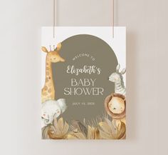 a baby shower sign hanging on a wall next to a white wall with an elephant and giraffe design