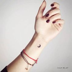 a woman's arm with a wristband and a small crescent tattoo on it