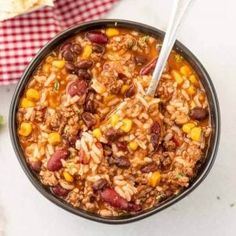 a bowl filled with chili and rice next to a spoon