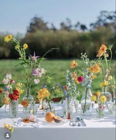 there are many vases with flowers in them sitting on the table outside by the grass