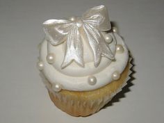 a cupcake with white frosting and a bow on top