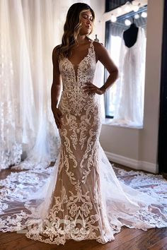 a woman standing in front of a window wearing a wedding dress