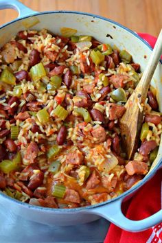 a large pot filled with beans and rice next to a wooden spoon on top of a red towel