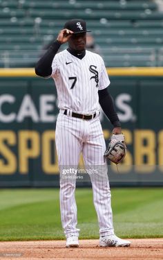 a baseball player standing on the field with his glove up to his ear and looking down