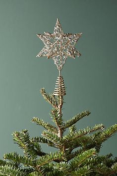 a christmas tree with an ornament hanging from it's top, against a green background