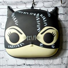 a black and white cat mask hanging on a brick wall