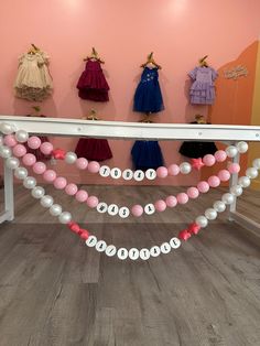 several dresses and balloons are on display in a room with pink walls, wooden floors and flooring