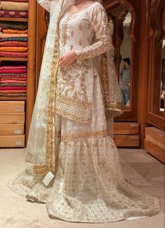 a woman in a white and gold outfit standing next to a closet full of clothes