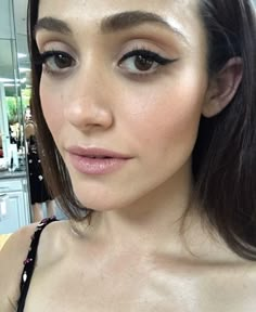 a close up of a woman with long dark hair and brown eyes wearing a black dress