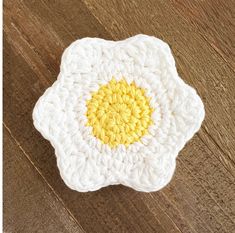 a crocheted dishcloth with an egg in the center on a wooden surface