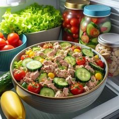 a bowl of tuna salad with cucumbers, tomatoes and lettuce