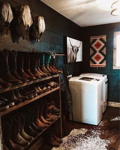 a washer and dryer in a room with boots on the wall next to it