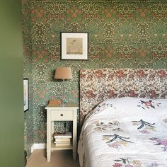 a bed sitting next to a night stand with a lamp on top of it in a bedroom