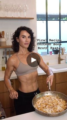 a woman standing in front of a kitchen counter holding a frying pan filled with food