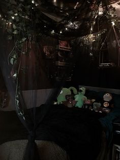 an unmade bed in a dark room with lights on the ceiling and stuffed animals