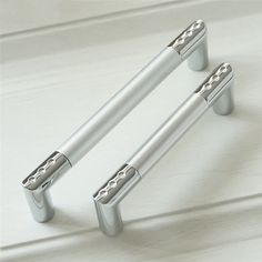 two metal handles on a white surface with the words mmf's above them