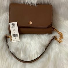 Tory Burch Emerson Convertible Chain Wallet Crossbody *New With Tags, Unworn *Moose Brown Saffiano Leather Exterior *Moose Brown Saffiano Leather And Nylon Interior *Interior: (6) Card Slots, (1) Zip Slot *Exterior: (1) Slip Slot *Magnetic Gold-Tone Snap Closure, Gold-Tone Hardware *Detachable Moose Brown Saffiano And Gold-Tone Shoulder Strap *Approximate Dimensions: 7.5" X 5.5" X 1" *Can Be Convertible Into Clutch Or Crossbody Classic Tan Wallet On Chain For Everyday Use, Wallet On Chain With Branded Hardware For Everyday Use, Classic Brown Wallet On Chain With Chain Strap, Classic Brown Wallet On Chain, Elegant Brown Wallet On Chain With Chain Strap, Classic Brown Wallet On Chain With Detachable Strap, Chic Brown Crossbody Wallet On Chain, Elegant Brown Wallet On Chain With Detachable Strap, Brown Crossbody Wallet On Chain For Travel