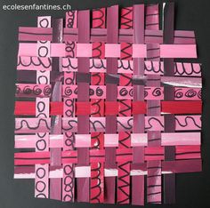 a piece of art made out of pink and red strips of paper with black letters