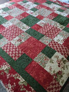 a large red and green quilt on top of a bed