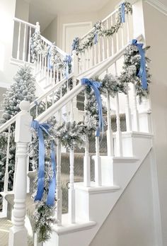 christmas decorations on the banisters and stairs are decorated with blue ribbon, pine cones and white balconies